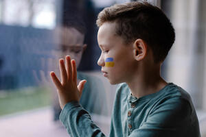 the child sits at the window with the flag of ukraine. State sup